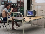 A man eats his lunch and watches TV on a street, 2008