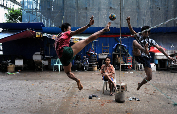 In einer Seitenstraße im Zentrum der birmanischen Hauptstadt Rangun (Yangon) spielen junge, birmanische Männer Takraw, 22. September, 2013. Dabei handelt es sich um eine sehr beliebte asiatische Ballsportart, die in Birma (Myanmar) auch unter dem Namen Chin Lone bekannt ist. Zwei Mannschaften aus jeweils drei Spielern versuchen mit maximal drei Berührungen den Ball aus Hartplastik über das Netz in das Spielfeld des Gegners zu schlagen.