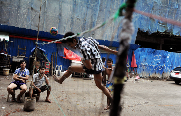 In einer Seitenstraße im Zentrum der birmanischen Hauptstadt Rangun (Yangon) spielen junge, birmanische Männer Takraw, 22. September, 2013. Dabei handelt es sich um eine sehr beliebte asiatische Ballsportart, die in Birma (Myanmar) auch unter dem Namen Chin Lone bekannt ist. Zwei Mannschaften aus jeweils drei Spielern versuchen mit maximal drei Berührungen den Ball aus Hartplastik über das Netz in das Spielfeld des Gegners zu schlagen.