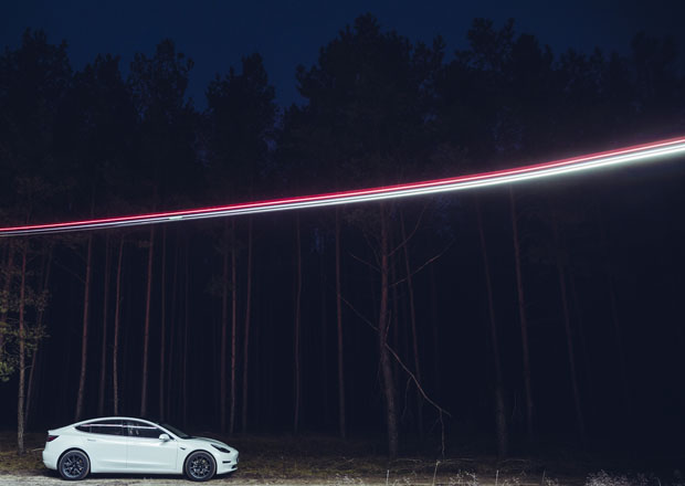 Ein Tesla Model 3 beleuchtet von einer Drohne steht im Januar 2020 auf einem Waldweg nahe Grünheide in Brandenburg.